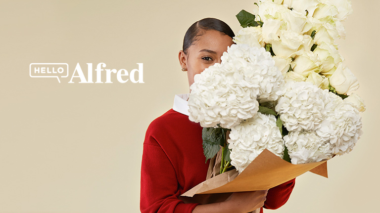 Close-up of a woman holding a flower bouquet to cover the side of her face